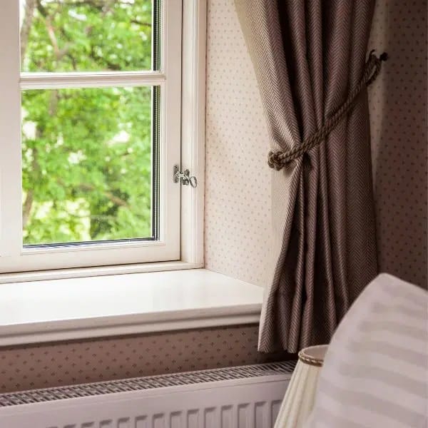 Rideau marron accroché par une attache sur le côté du mur avec radiateur situé au-dessous