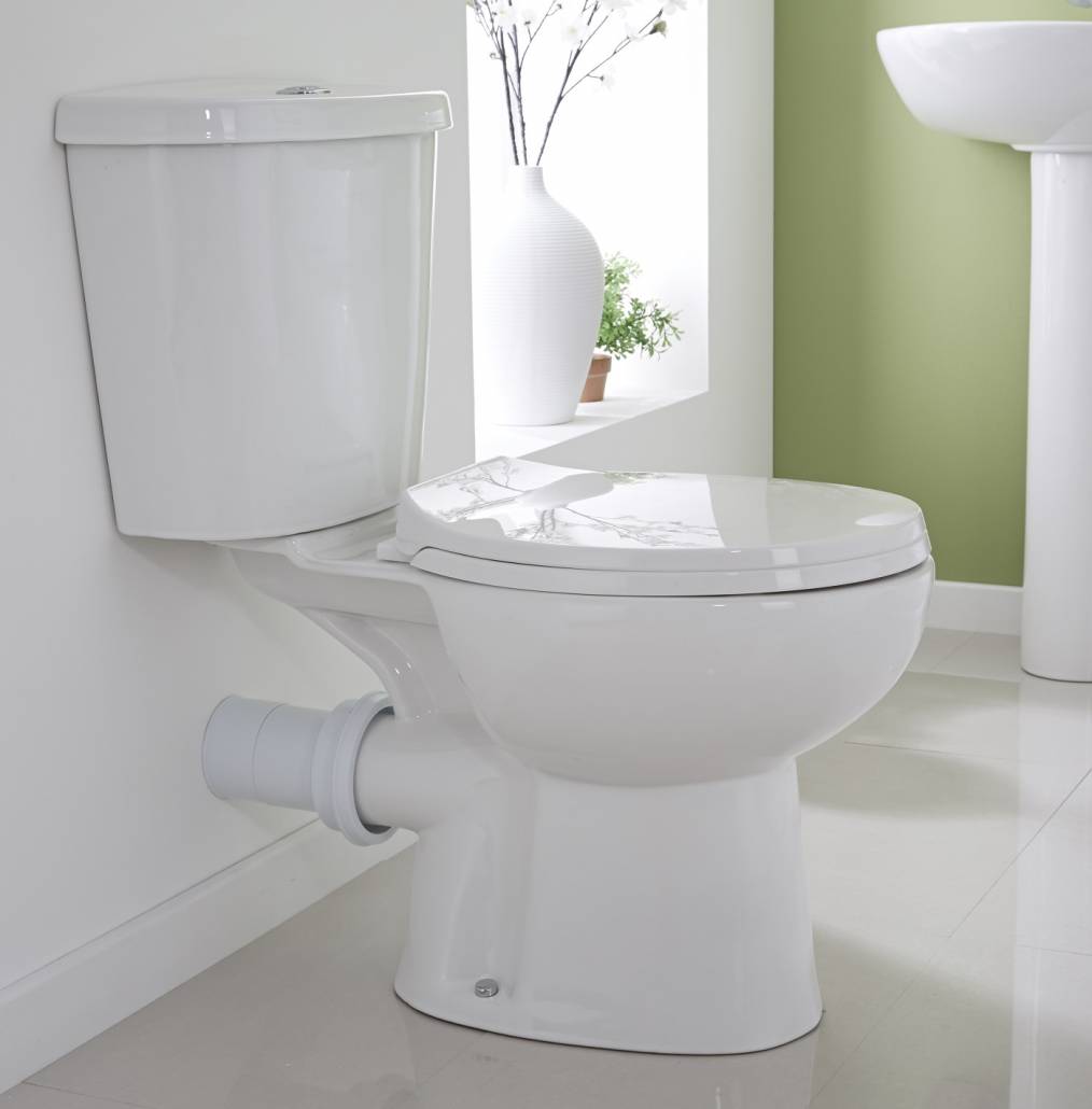 Cuvette de toilettes à poser rattachée à un mur en faux carreaux de ciment et lavabo posé dur une étagère