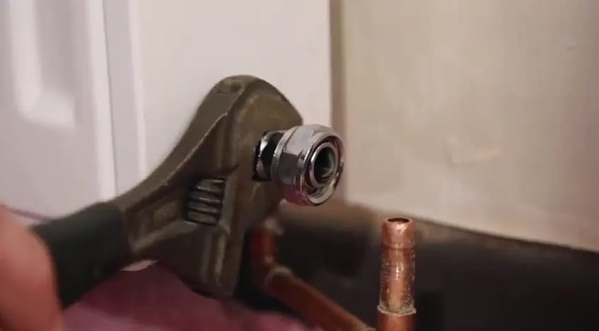 Clé à molette au niveau de l’écrou du robinet d’arrêt qui est déconnecté du tuyau