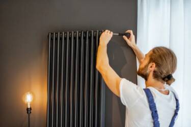 Personnel qualifié tenant un tournevis sur la partie supérieure d’un radiateur noir