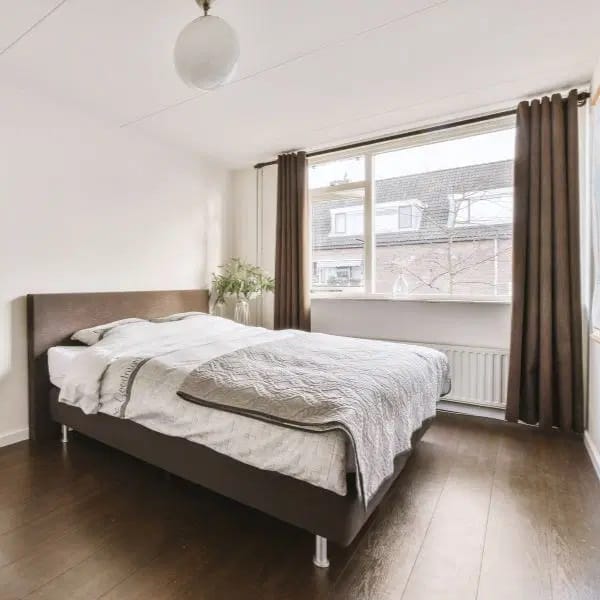 Chambre à coucher avec longs rideaux marrons tombants de chaque côté du radiateur